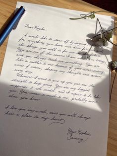 a piece of paper with writing on it sitting next to a pen and flower pot