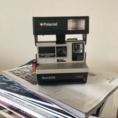 an old polaroid camera sitting on top of magazines