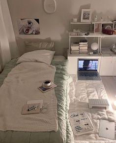 a laptop computer sitting on top of a bed next to a white book shelf filled with books