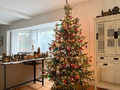 a decorated christmas tree in a living room next to a table with ornaments on it