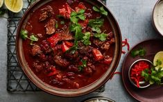 a bowl filled with meat and vegetables on top of a table next to other dishes