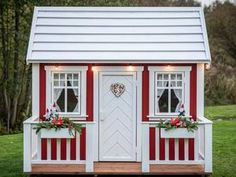 a small red and white house with two windows on the front, decorated for christmas