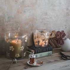 two candles are sitting on a table next to some books and other items that have been placed around them