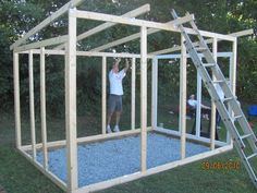 a man standing in front of a wooden structure with a ladder on the side and another person climbing up to it