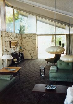 a living room filled with furniture next to a large glass window covered in light coming from the ceiling