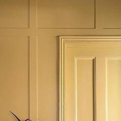 a clock sitting on top of a wooden table next to a wall with white paneling