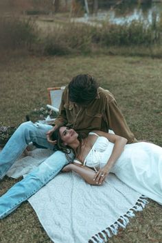 a woman laying on top of a blanket next to a man