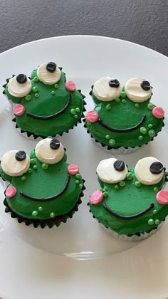 green cupcakes with white frosting decorated like a frog and black eyes on a plate