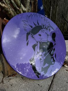 a purple frisbee sitting on the ground next to a tree