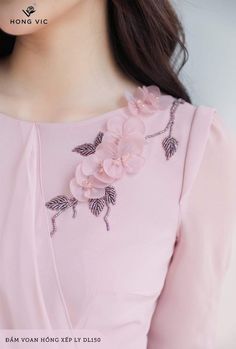 a woman wearing a pink dress with flowers on the chest and long sleeved top