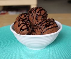 chocolate ice cream balls in a white bowl on a blue place mat