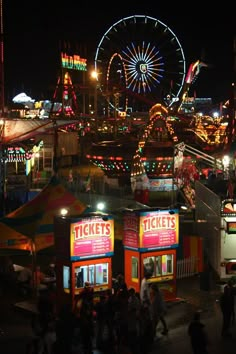 an amusement park at night with people walking around