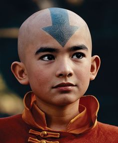 a young man with a bald head has a blue arrow on his forehead