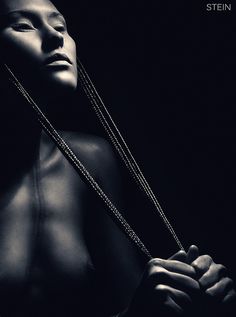 a black and white photo of a woman holding two necklaces to her chest with the words sten on it