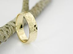 a gold wedding ring sitting on top of a piece of driftwood next to a twig