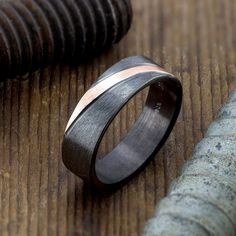 a wedding band with two tone gold and silver inlays on a wooden surface