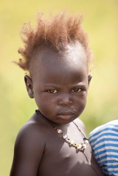 a young child with red hair standing in the grass