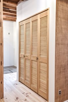 an empty room with wooden doors and wood flooring on the walls, in front of a white wall