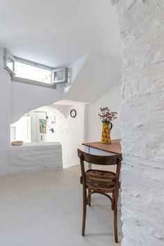 a chair and table in a room with white walls, windows and a skylight