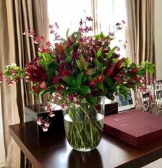 a vase filled with red flowers sitting on top of a table next to a book