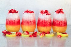 three drinks with strawberries and lemon slices on the rims are lined up next to each other