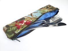 a knife and fork in a zippered pouch on a white surface with spoons