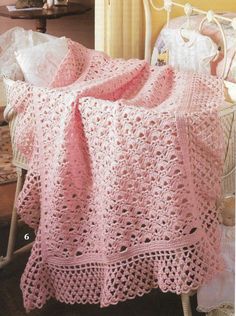 a pink crocheted blanket sitting on top of a chair