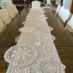 a long table with white lace on it in the middle of a living room and dining room