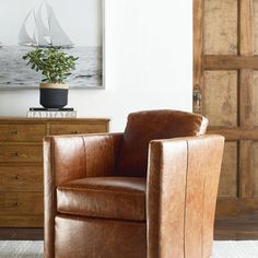 a brown leather chair sitting in front of a wooden dresser with a potted plant on top of it