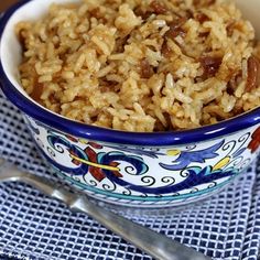 a bowl filled with rice and raisins on top of a blue table cloth