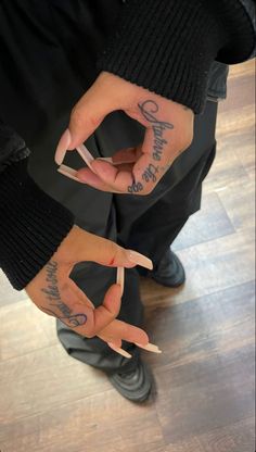 two people with tattoos on their hands and one is holding something in the other hand