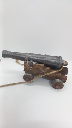 an old cannon is tied up to a wooden block with rope on it and sits on a white surface