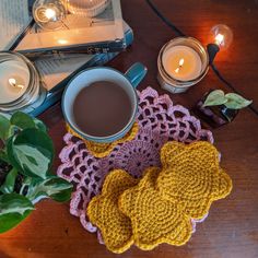 a cup of coffee sitting on top of a wooden table next to a book and some candles