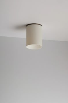 a white lamp hanging from the ceiling in a room with gray walls and flooring