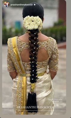 the back of a woman's head with braids and flowers in her hair