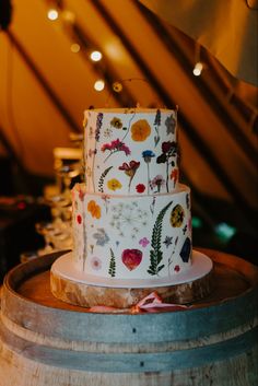 a three tiered cake sitting on top of a wooden barrel