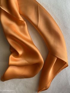 Luxurious natural mulberry silk square scarf, color orange, size: 65 cm x 65 cm / 26 in x 26 in. Soft, smooth, and lustrous silk charmeuse fabric, breathable and skin-friendly feels very soft and comfortable to wear. Can style in many ways: you can wear this scarf as a soft neck scarf, as a hair tie, as a headband scarf, as a wrist scarf, as a purse accessory. Or style it in any way you want with your own sense of creativity! Suitable for all seasons and is a great gift idea for special occasions. Care Instructions: Pure silk is a type of organic, natural and delicate fabric, please avoid washing. Dry clean recommended. Stored in a cool, dry, and dark place. To smooth out wrinkles and creases naturally, you may hang the scarf for a while as it will straighten out on its own. Ironing revers Satin Silk Scarf Gift, Silk Scarves Perfect For Gifts, Solid Silk Scarf Gift, Elegant Orange Summer Scarf, Solid Color Silk Scarf For Formal Summer Occasions, Silk Orange Scarves As A Gift, Orange Silk Scarves As A Gift, Silk Orange Scarves As Gift, Orange Silk Scarves As Gift