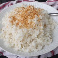 a white plate topped with rice on top of a red and white checkered table cloth