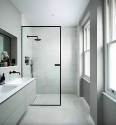 a bathroom with a walk in shower next to two sinks