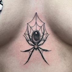 a spider tattoo on the back of a woman's chest, with an orb in the center