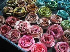 there are many different colors of rolled flowers in the box on the table and one is pink, green, blue, yellow