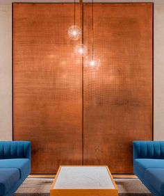 a living room with two blue couches and a coffee table in front of a wooden paneled wall