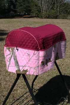 a pink and red blanket sitting on top of a metal stand in the middle of a field