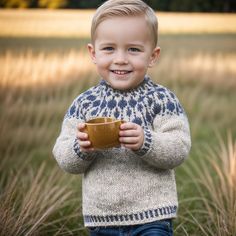 a young boy is holding a bowl in his hands and smiling at the camera while standing in tall grass