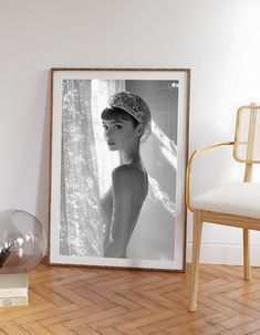 a black and white photo of a woman wearing a head scarf in a room with a chair