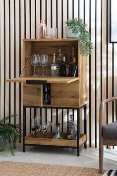 a wooden cabinet with wine glasses and liquor bottles in it next to a striped wall