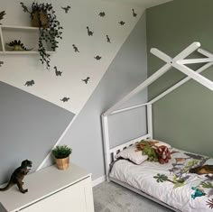 a child's bedroom with dinosaur themed wallpaper and white bed frame in the corner