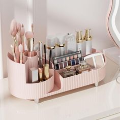 a pink tray with makeup brushes, lipstick and other items in it on a white counter