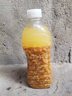 a plastic bottle filled with liquid sitting on top of a cement floor next to a wall