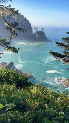 the ocean is blue and green with waves coming in from the rocks on the shore